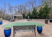 Thumbnail 22 of 30 - A park with a gazebo, benches, and a green table surrounded by trees.