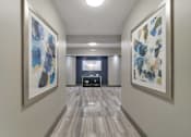Thumbnail 5 of 30 - A hallway with two paintings on the wall and a bench in the middle.