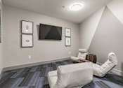 Thumbnail 9 of 30 - A room with a chair and a television on the wall.