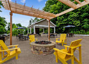 Thumbnail 13 of 30 - A patio with yellow chairs and a fire pit.