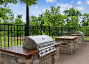 Thumbnail 20 of 30 - A black metal fence surrounds a stone and wood outdoor kitchen.