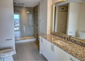 Thumbnail 6 of 18 - A bathroom with a toilet, sink, and mirror.