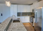 Thumbnail 8 of 18 - A kitchen with a granite counter top and stainless steel appliances.