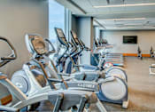 Thumbnail 11 of 18 - A gym with a row of stationary bikes and a television mounted on the wall.