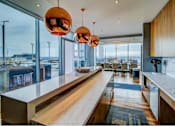 Thumbnail 15 of 18 - A modern kitchen with a long counter and pendant lights.