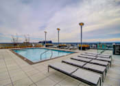 Thumbnail 16 of 18 - A pool with sun loungers and lights on the side.
