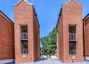 Thumbnail 7 of 25 - two red brick buildings with balconies and a blue sky
