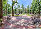 Thumbnail 10 of 25 - a courtyard with benches and trees with an apartment building in the background