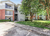 Thumbnail 22 of 23 - Apartment complex with a parking lot in front.
