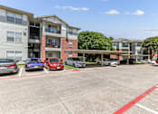 Thumbnail 23 of 23 - A parking lot with cars and apartment buildings in the background.