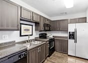 Thumbnail 13 of 23 - A kitchen with a white refrigerator and brown cabinets.