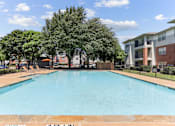 Thumbnail 11 of 23 - A large swimming pool surrounded by trees and apartment buildings.