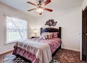 Thumbnail 7 of 19 - A bedroom with a bed, pillows, and a ceiling fan.