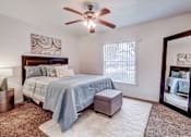 Thumbnail 9 of 19 - A bedroom with a bed, a ceiling fan, and a mirror.