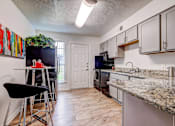 Thumbnail 2 of 19 - A kitchen with granite countertops and a black fridge.
