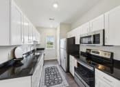 Thumbnail 12 of 20 - a kitchen with white cabinets and black counter tops