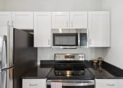 Thumbnail 13 of 20 - a kitchen with white cabinets and a stove and a microwave