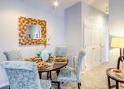 Thumbnail 16 of 23 - A dining room with a table set for two and a mirror above it.