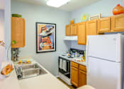 Thumbnail 17 of 23 - A kitchen with a white fridge, a sink and a microwave.