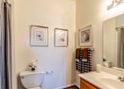 Thumbnail 22 of 23 - A bathroom with a toilet, sink, and three pictures on the wall.