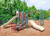 Thumbnail 3 of 23 - A playground with two slides and a climbing structure.