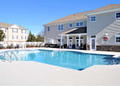 Thumbnail 3 of 36 - A swimming pool in front of a building with a red and white sign.