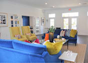 Thumbnail 16 of 36 - A living room with blue couches and yellow chairs.