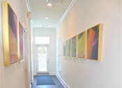 Thumbnail 18 of 36 - A hallway with a series of paintings on the wall.