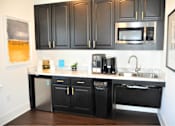 Thumbnail 26 of 36 - A kitchen with black cabinets and a stainless steel dishwasher.