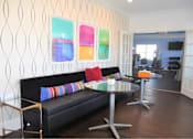 Thumbnail 27 of 36 - A black couch with colorful pillows sits in front of a wall with three colorful paintings.