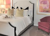 Thumbnail 31 of 36 - A bedroom with a white bed and a pink chair.