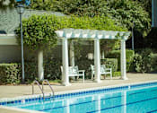 Thumbnail 15 of 28 - A pool with a white pergola and chairs.