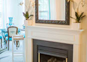 Thumbnail 7 of 28 - A fireplace with a mirror above it and flowers on the mantle.