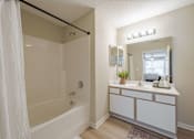 Thumbnail 9 of 40 - A white bathroom with a tub, sink, and mirror.