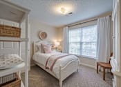 Thumbnail 10 of 40 - A bedroom with a white bed and a window with white curtains.