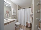 Thumbnail 12 of 40 - A white bathroom with a toilet, sink, and shower curtain.