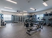 Thumbnail 21 of 40 - A spacious gym with a variety of equipment including treadmills, weights, and exercise machines.