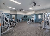 Thumbnail 23 of 40 - A spacious gym with a variety of equipment and a ceiling fan.