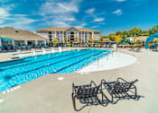 Thumbnail 49 of 64 - A large swimming pool with lounge chairs and a building in the background.