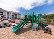 Thumbnail 57 of 64 - A green playground slide in the middle of a playground.