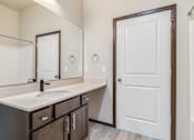 Thumbnail 17 of 25 - A bathroom with a sink, mirror, and door.