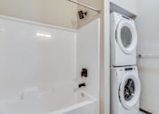 Thumbnail 8 of 25 - A white washing machine in a small bathroom.