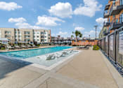 Thumbnail 20 of 26 - A pool area with a clear blue sky and white clouds.