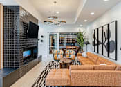 Thumbnail 10 of 53 - Brookside, Kansas City, MO, Apartments Near Rockhurst University - Brookside Commons - A Resident Lounge with a Fireplace, Mounted TV, Large Couch, Armchairs, Coffee Table, and Home Decor.