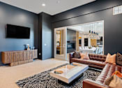 Thumbnail 15 of 53 - A modern living room with a brown leather couch and a black and white rug.