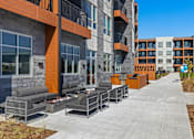 Thumbnail 26 of 53 - Studio Apartments in Brookside, Kansas City, MO - Brookside Commons - Outdoor Lounge with Fire Pits, Outdoor Couch, and Armchairs, Overlooking the Grilling Station.