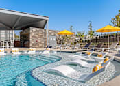 Thumbnail 27 of 53 - Two-Bedroom Apartments in Brookside, Kansas City, MO - Brookside Commons - Swimming Pool with In-Water Loungers, Sun Loungers, and Umbrellas, Overlooking the Covered Patio Area.