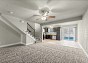Thumbnail 6 of 47 - A spacious room with a staircase and a ceiling fan.