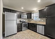 Thumbnail 35 of 47 - Peculiar, MO, Townhomes Near Raymore-Peculiar School District - Bradley’s Crossing - Kitchen with Vinyl Plank Flooring, Granite Countertop, Custom Cabinetry, and Stainless Steel Appliances.