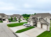 Thumbnail 1 of 47 - A white car is parked in front of a house in a residential neighborhood.